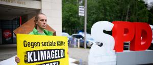 Ein Aktivist hält bei einer Protestaktion der Umweltschutz-Organisation Greenpeace vor der SPD-Zentrale ein Schild mit der Aufschrift „Gegen soziale Kälte - Klimageld jetzt!“. Greenpeace-Aktivisten haben vor der SPD-Zentrale in Kreuzberg etwa eine Tonne Eis ausgeschüttet und ein gefrorenes „S“ vom SPD-Schriftzug aufgestellt, um für die Einführung des Klimagelds zu demonstrieren.