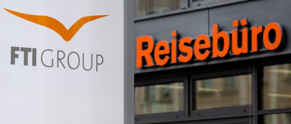 Das Logo des Reiseveranstalter FTI (FTI Group) steht an der Firmenzentrale vor einem Reisebüro.