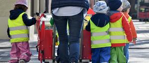 Eine Betreuerin läuft mit mehreren Kleinkindern über einen Bürgersteig. (Symbolbild)