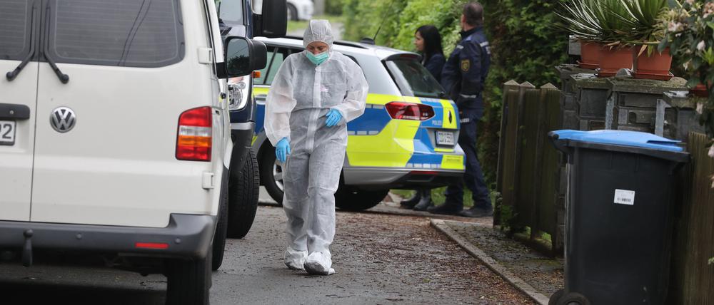 Polizeibeamte der Spurensicherung stehen an einem Tatort auf der Straße. In einem nahe gelegenen Haus war es zu einem Gewaltverbrechen mit drei Toten gekommen.