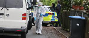 Polizeibeamte der Spurensicherung stehen an einem Tatort auf der Straße. In einem nahe gelegenen Haus war es zu einem Gewaltverbrechen mit drei Toten gekommen. 
