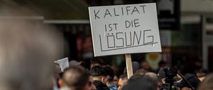 Teilnehmer einer Islamisten-Demo halten ein Plakat mit der Aufschrift „Kalifat ist die Lösung“ in die Höhe. 