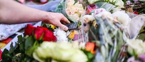 Bei einer Kundgebung unter dem Motto „Mannheim hält zusammen“, die anlässlich einer Messerattacke stattfindet bei der ein Polizist getötet wurde, legt ein Passant ein Polizeiwappen zu nieder gelegten Blumen.