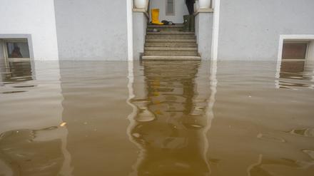 Im Treppenaufgang eines Hauses, dessen Untergeschoss voll Wasser ist, stehen Gummistiefel. 