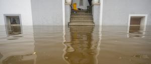 Im Treppenaufgang eines Hauses, dessen Untergeschoss voll Wasser ist, stehen Gummistiefel. 