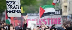 Demonstranten halten am 1. Mai 2023 in Berlin ein Plakat mit der Aufschrift „Boycott Israeli Apartheid“ hoch.