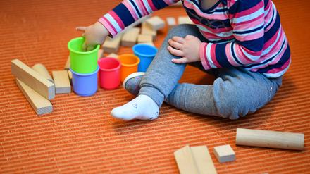 ARCHIV - 20.10.2017, Baden-Württemberg;Thüringen, ---: Ein Mädchen spielt in einer Kita mit bunten Bechern und Bauklötzen. (zu dpa: «Kitas, Klima und Kliniken: Vor diesen Problemen stehen die Kommunen») Foto: Uwe Anspach/dpa +++ dpa-Bildfunk +++