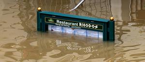 Ein Schild mit der Speisekarte eines Restaurants steht im Hochwasser der Donau.