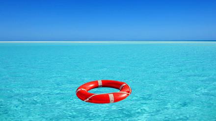 Roter Rettungsring treibt auf türkisblauem Wasser im Meer. 