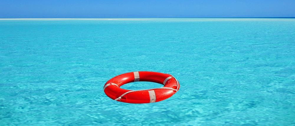 Roter Rettungsring treibt auf türkisblauem Wasser im Meer. 