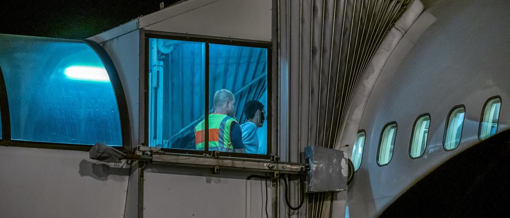 Polizeibeamte begleiten einen Afghanen auf dem Flughafen Leipzig-Halle in ein Charterflugzeug. 