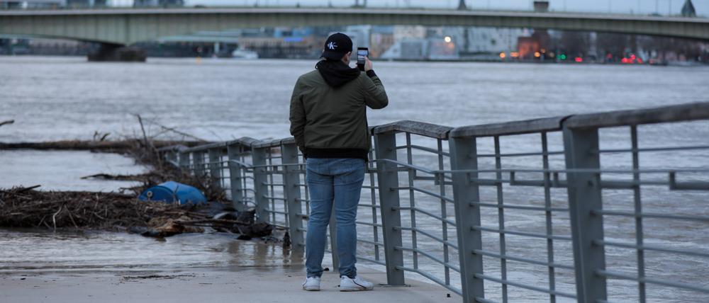 Hochwasser-Tourist fotografieren mit ihren Handys die Flut in Köln im Februar 2021.