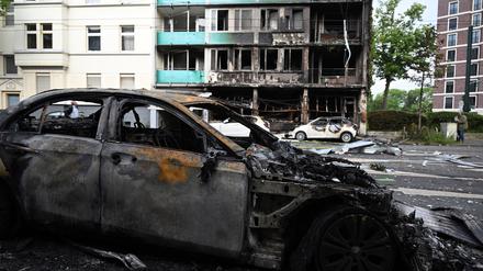 Ausgebrannte Autos stehen vor einem Wohnhaus, in dem ein Brand wütete. Bei dem Brand in Düsseldorf sind mehrere Menschen ums Leben gekommen und weitere verletzt worden. 