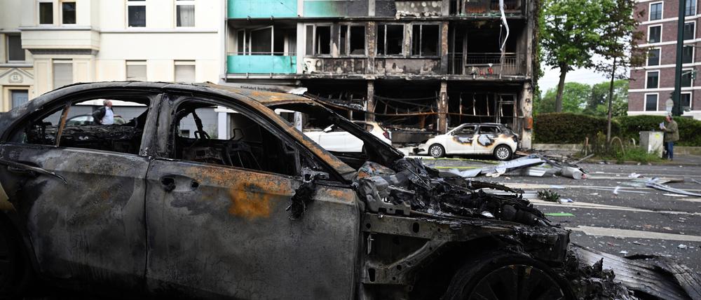 Ausgebrannte Autos stehen vor einem Wohnhaus, in dem ein Brand wütete. Bei dem Brand in Düsseldorf sind mehrere Menschen ums Leben gekommen und weitere verletzt worden. 