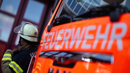 Eine Einsatzkraft der Feuerwehr steht neben einem Einsatzfahrzeug der Feuerwehr. (Symbolbild)