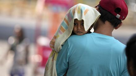 Ein Mann in Jammu, Indien, trägt ein Kind, dessen Kopf mit einem Handtuch bedeckt ist, um es vor der Hitze zu schützen, die das Land Anfang Juni heimgesucht hat.