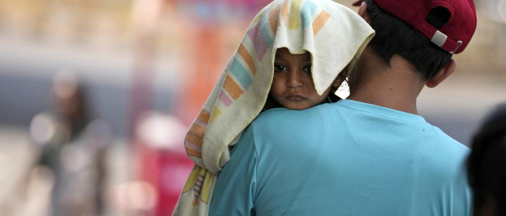 Ein Mann in Jammu, Indien, trägt ein Kind, dessen Kopf mit einem Handtuch bedeckt ist, um es vor der Hitze zu schützen, die das Land Anfang Juni heimgesucht hat.