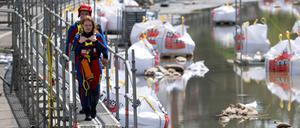 Rettungsschwimmer der DLRG gehen am Donauufer in Regensburg über einen Hochwassersteg.