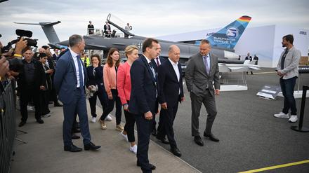 Schönefeld: Bundeskanzler Olaf Scholz (SPD, M.) geht während des Eröffnungsrundgangs auf der Internationalen Luft- und Raumfahrtausstellung (ILA) auf dem Gelände vom Flughafen Berlin Brandenburg (BER) vor einem Eurofighter entlang.