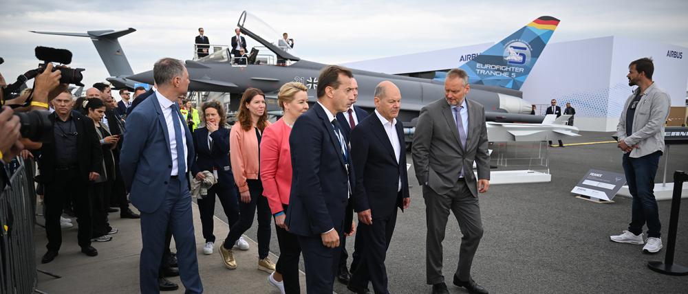 Schönefeld: Bundeskanzler Olaf Scholz (SPD, M.) geht während des Eröffnungsrundgangs auf der Internationalen Luft- und Raumfahrtausstellung (ILA) auf dem Gelände vom Flughafen Berlin Brandenburg (BER) vor einem Eurofighter entlang.