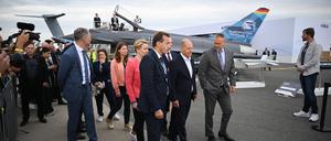 Schönefeld: Bundeskanzler Olaf Scholz (SPD, M.) geht während des Eröffnungsrundgangs auf der Internationalen Luft- und Raumfahrtausstellung (ILA) auf dem Gelände vom Flughafen Berlin Brandenburg (BER) vor einem Eurofighter entlang.