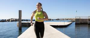 Eine Sportlerin joggt über einen Bootssteg.