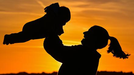 Eine Mutter ist mit ihrem Baby im Sonnenuntergang zu sehen. 