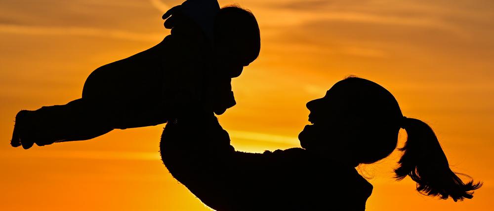 Eine Mutter ist mit ihrem acht Monate alten Baby im Sonnenuntergang auf einem Feldweg zu sehen.