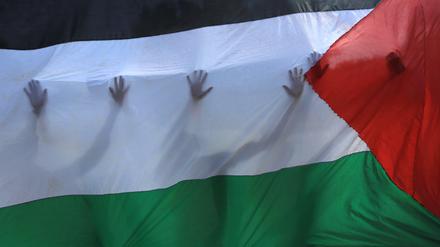 Menschen hinter einer palästinensischen Fahne. In den vergangenen Wochen hatten Norwegen, Spanien, Irland und Slowenien beschlossen, Palästina als Staat anzuerkennen, was heftigen Protest Israels ausgelöst hatte. 