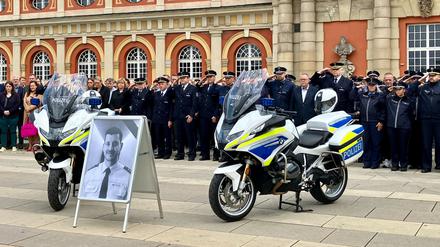 07.06.2024, Brandenburg, Potsdam: Polizisten und Brandenburgs Innenminister Michael Stübgen (Mitte r) gedenken vor dem Filmmuseum dem getöteten Polizisten Rouven Laur. 