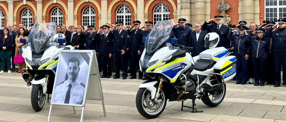07.06.2024, Brandenburg, Potsdam: Polizisten und Brandenburgs Innenminister Michael Stübgen (Mitte r) gedenken vor dem Filmmuseum dem getöteten Polizisten Rouven Laur. 