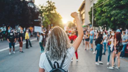 Eine junge Frau mit erhobener Faust bei einem Protestmarsch. 