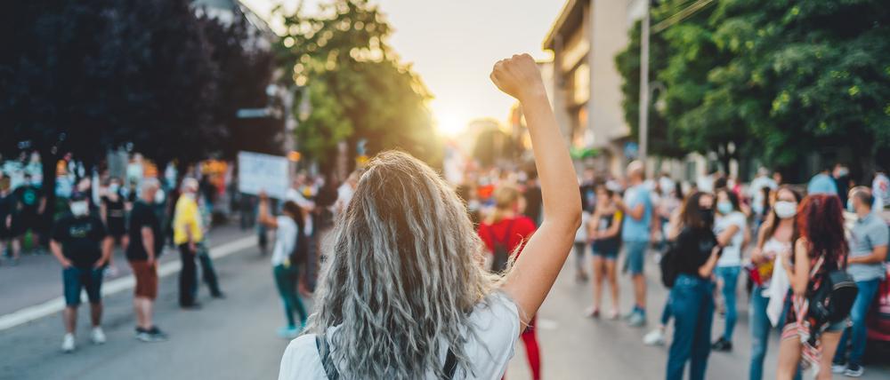 Eine junge Frau mit erhobener Faust bei einem Protestmarsch.