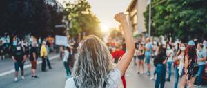 Eine junge Frau mit erhobener Faust bei einem Protestmarsch. 