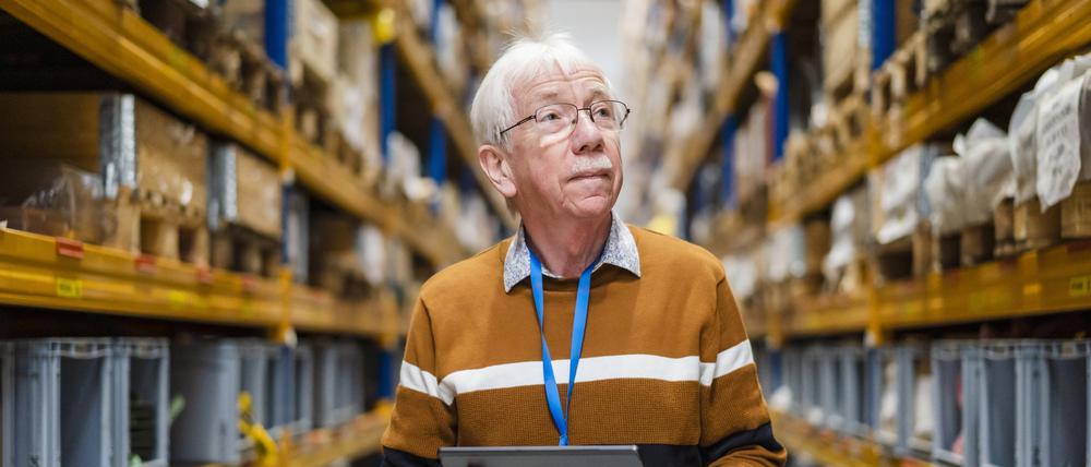 Ein Senior mit einem Tablet in einer Lagerhalle (Symbolfoto).