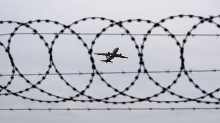 Ein Flugzeug startet – fotografiert durch Stacheldraht am Flughafenzaun (Symbolbild).