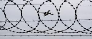 Ein Flugzeug startet – fotografiert durch Stacheldraht am Flughafenzaun (Symbolbild).