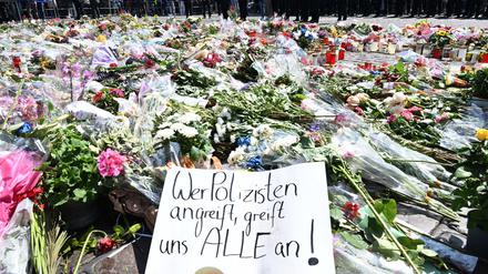 Blumen und Kerzen liegen bei einer Gedenkminute auf dem Marktplatz in Mannheim zum Gedenken an einen getöteten Polizisten. 