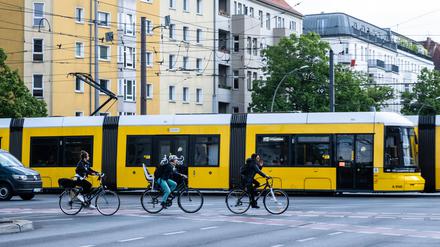 Sie könnten Kollegen sein: Radfahrer neben einer Straßenbahn der BVG in Berlin.