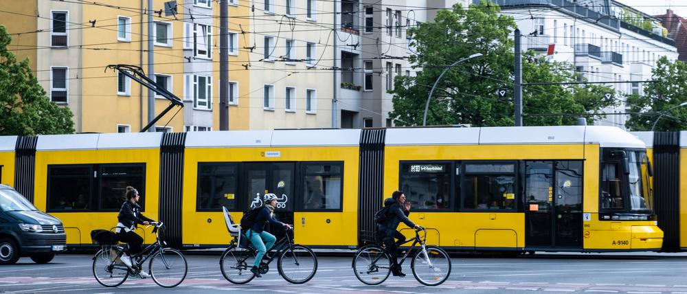 Sie könnten Kollegen sein: Radfahrer neben einer Straßenbahn der BVG in Berlin.
