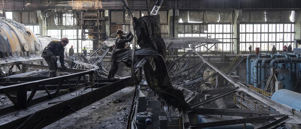 Arbeiter räumen die Trümmer nach einem russischen Raketenangriff auf das DTEK-Kraftwerk in der Ukraine auf.