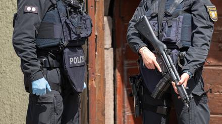 Eine Polizistin steht mit einer Maschinenpistole vor einer Tür. (Symbolbild)