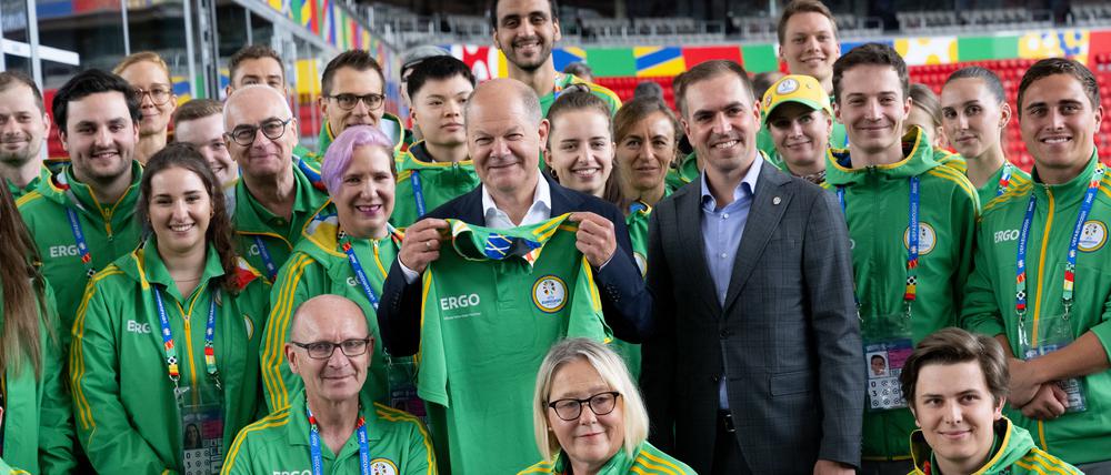 Da schaut selbst der Kanzler vorbei. Olaf Scholz (M.) und Philipp Lahm mit Volunteers in München.