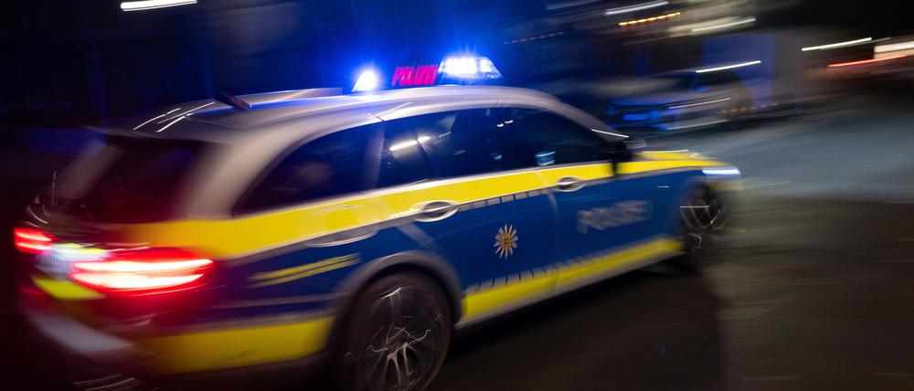  Ein Polizeifahrzeug fährt mit Blaulicht an einem Gebäude vorbei. (Symbolbild)