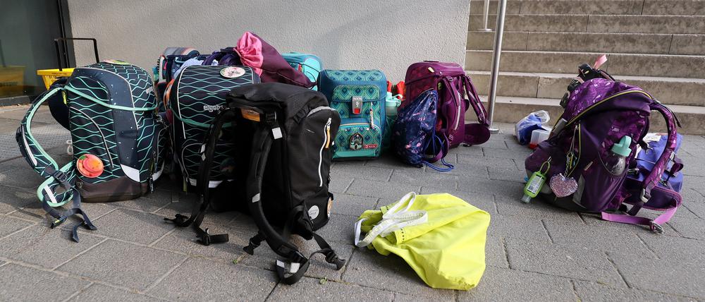 Schulranzen vor einer Schule.