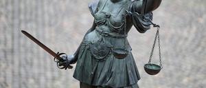 Eine Statue der Justitia hält eine Waage und ein Schwert in der Hand.