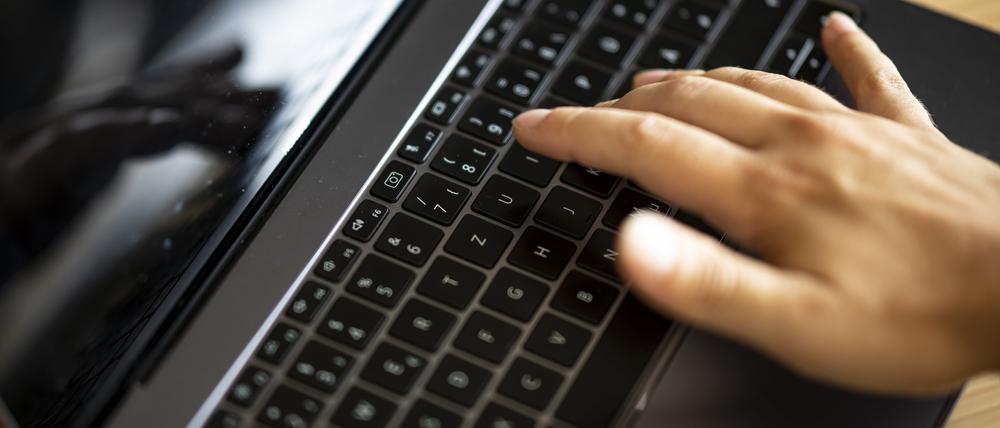 Ein Mann tippt auf der Tastatur eines Laptops. (Symbolbild)