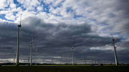Windräder werden bei wolkigem Himmel kurzzeitig von der tiefstehenden Sonne beleuchtet.