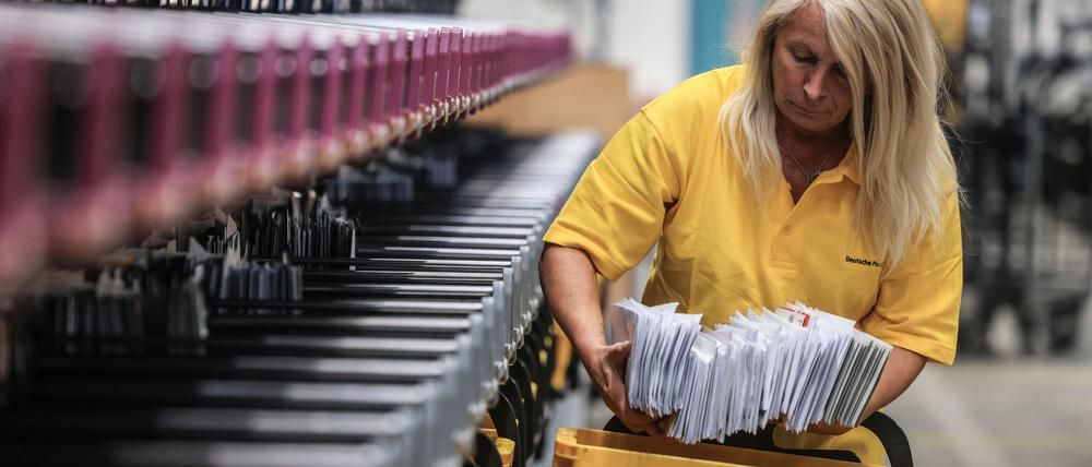 PRODUKTION - 09.04.2024, Nordrhein-Westfalen, Frechen: Eine Mitarbeiterin der Deutschen Post sortiert Briefe in einem Briefverteilzentrum. (zu dpa: «Bundestag stimmt über Reform des veralteten Postgesetzes ab») Foto: Oliver Berg/dpa +++ dpa-Bildfunk +++