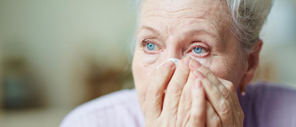 Eine Frau tupft sich Tränen aus dem Gesicht.